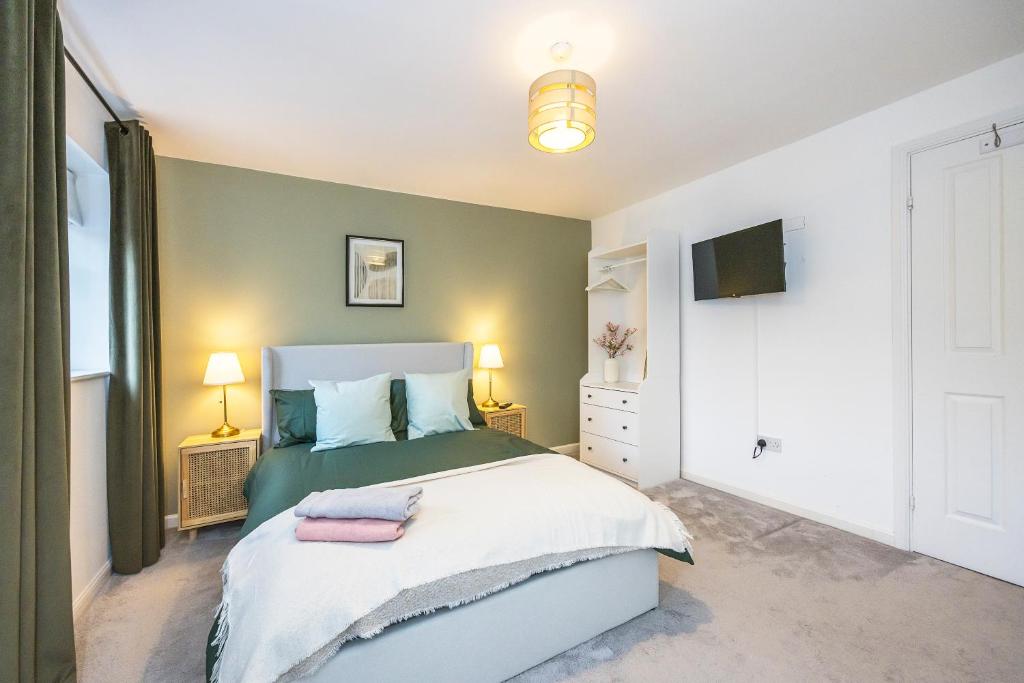 um quarto com uma cama verde e branca e uma televisão em The Lake Hub em Goodmayes