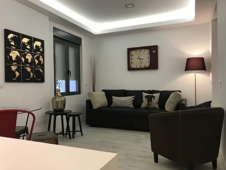 - un salon avec un canapé et un réveil sur le mur dans l'établissement Preciosos apartamento cerca de Atocha CAN, à Madrid