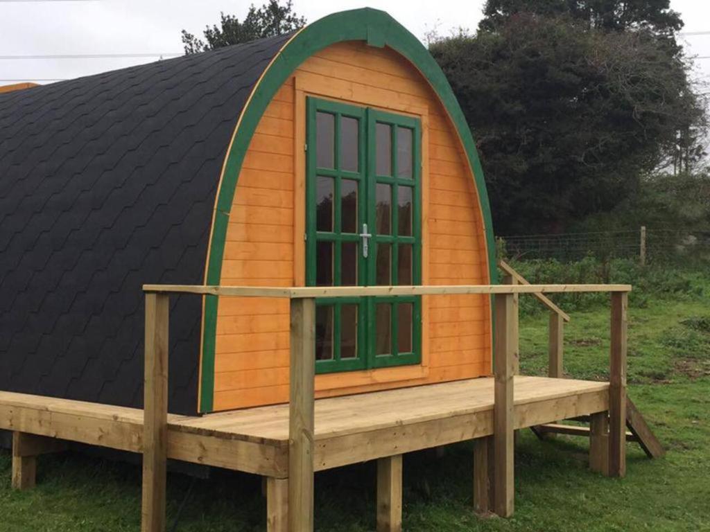 une petite maison en bois avec une fenêtre verte sur une plateforme en bois dans l'établissement Lovely Glamping Dream Pod in St Austell Cornwall, à St Austell