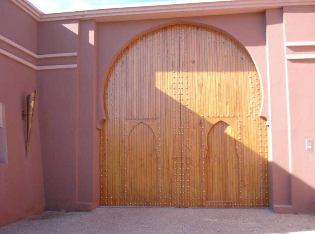 - une grande porte en bois dans une chambre avec un mur dans l'établissement Villa Pepe, à El Harkat