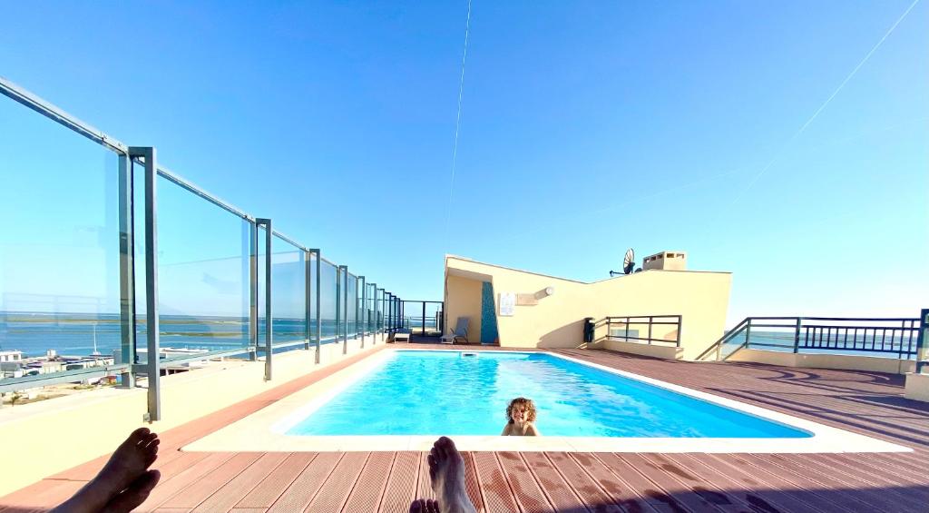 Una donna sdraiata in una piscina sopra una casa di Zenit Luxury Marina Village Appartement a Olhão