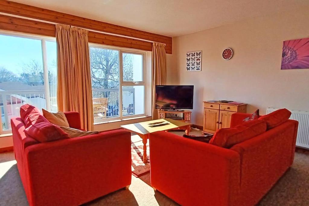 St Ann's 21 في Gunnislake: غرفة معيشة فيها كرسيين احمر وتلفزيون