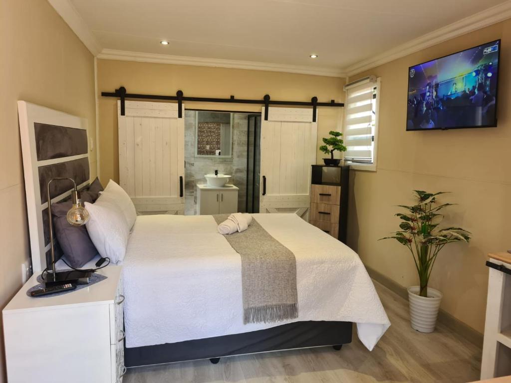 a bedroom with a bed and a tv on the wall at Country Cabin in Midrand