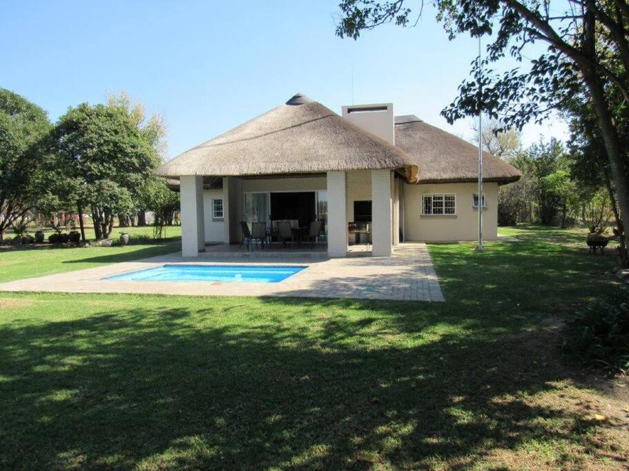 a house with a thatched roof and a yard at Lions Rest on Vaal River in Vanderbijlpark