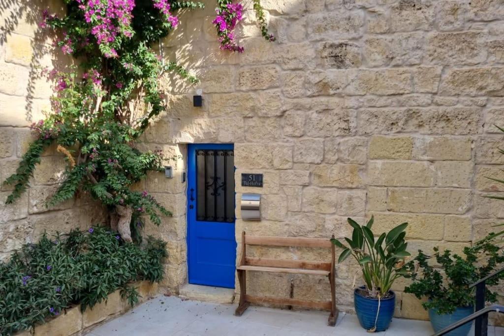 a blue door on a stone building with a bench at Cozy 1 Bedroom House in Iz-Zejtun in Żejtun