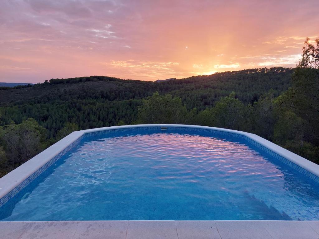 une piscine avec vue sur le coucher du soleil en arrière-plan dans l'établissement "Ca la calma" Cozy house in the mountains surrounded by forest, 