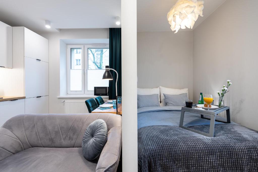 een woonkamer en een slaapkamer met een bank en een tafel bij JK Apartment Przytulny Katowice Ligota in Katowice
