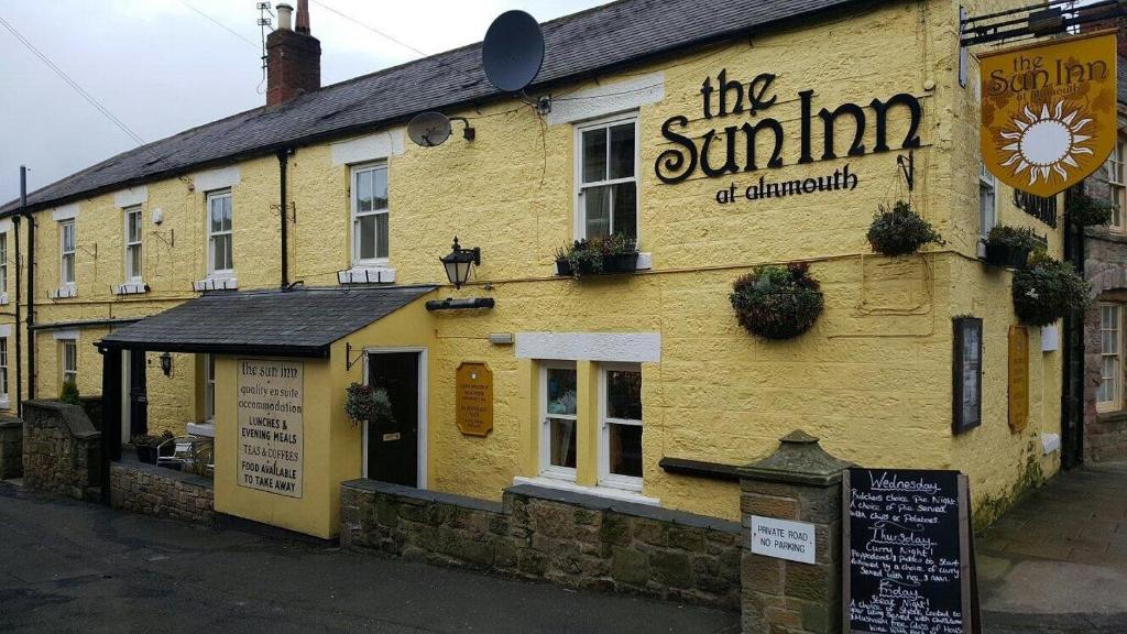 un edificio amarillo con un cartel en el costado en The Sun Rooms, en Alnmouth