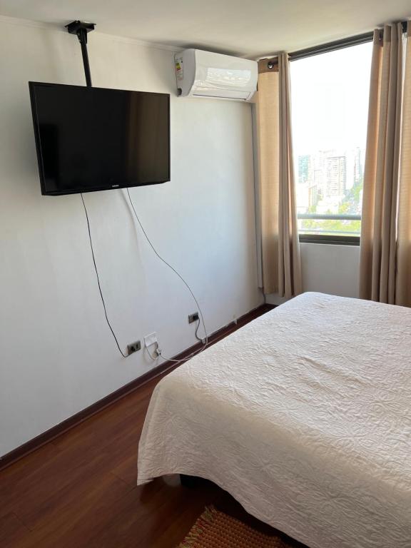 - une chambre avec un lit et une télévision murale à écran plat dans l'établissement Acogedor Depto excelente vista, A/C, à Santiago