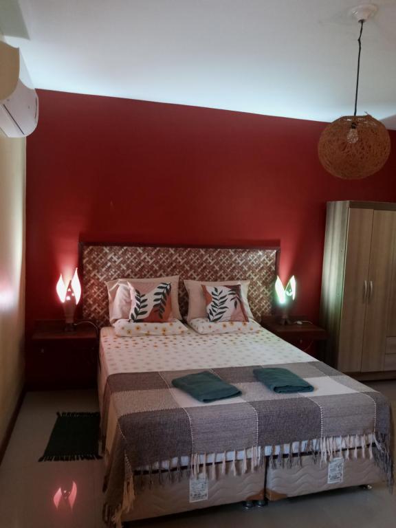 1 dormitorio con 1 cama grande y pared roja en Pipa Zen Guest House, en Pipa