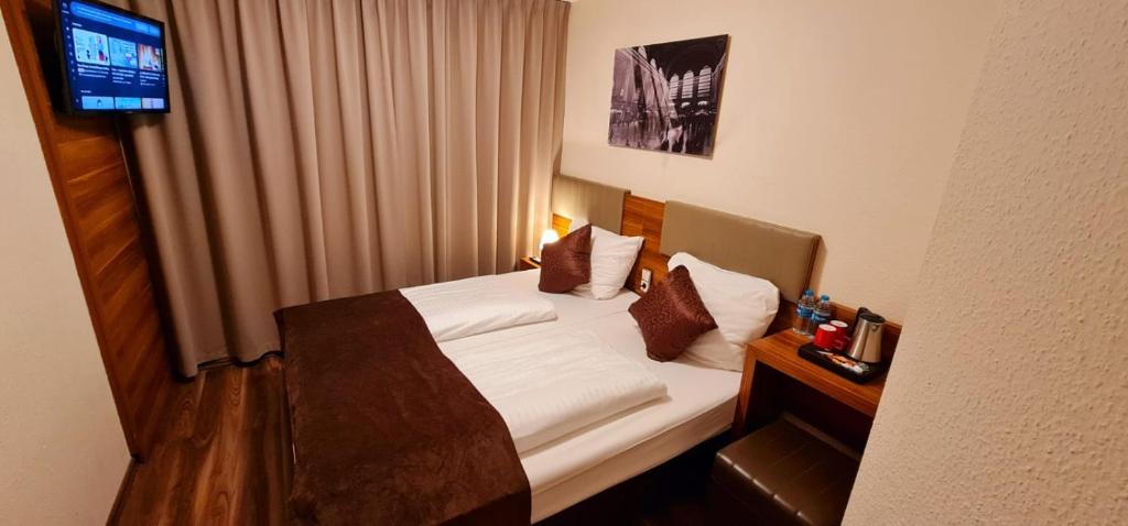 a hotel room with a bed and a television at Hotel Frankfurt Messe in Frankfurt