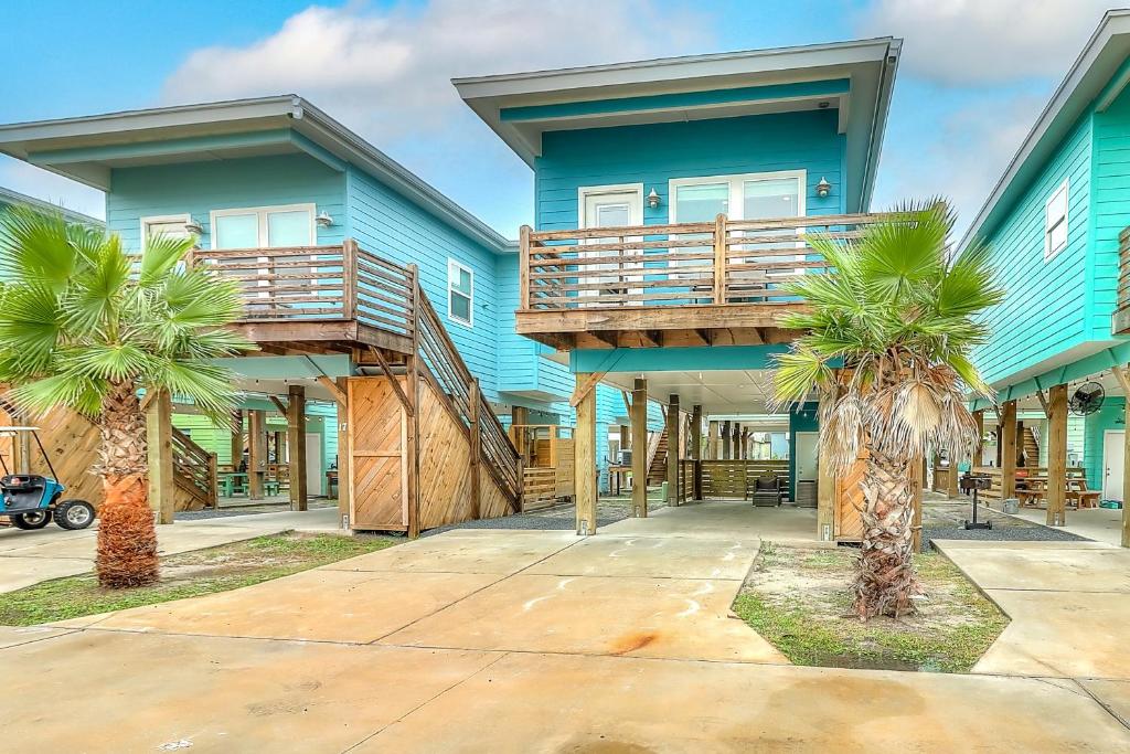 a blue house with a balcony and palm trees at Stack Overflow in Port Aransas