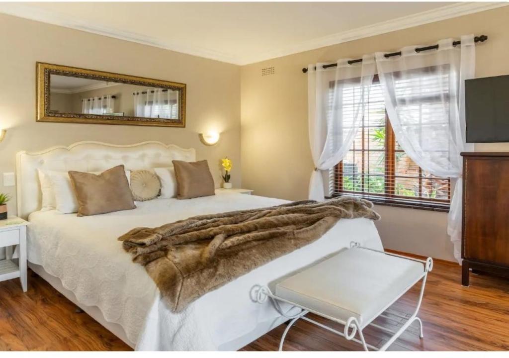 a bedroom with a white bed and a mirror at Meerendal Cottage-Affordable Luxury,Private Pool in Cape Town