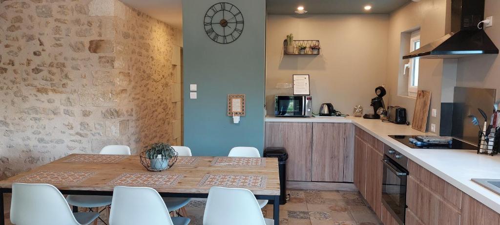 cocina con mesa de madera y sillas blancas en Gîte le Hameau des Bordes 4 étoiles, en Nouaillé-Maupertuis