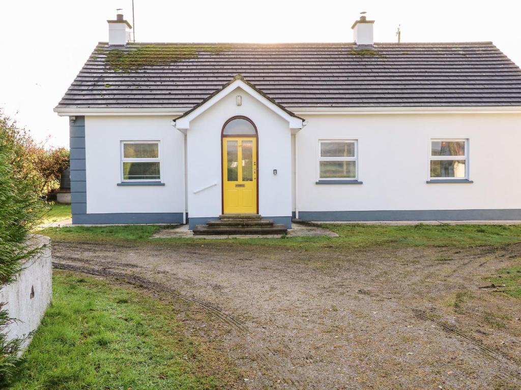 una casa blanca con una puerta amarilla en un camino de tierra en 17 Buninver Road, en Omagh