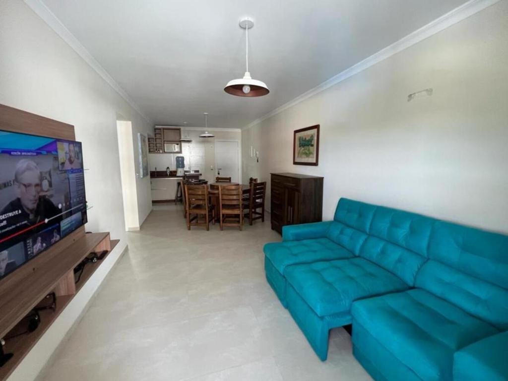 sala de estar con sofá azul y TV en Apartamento Manchester, en Bombinhas