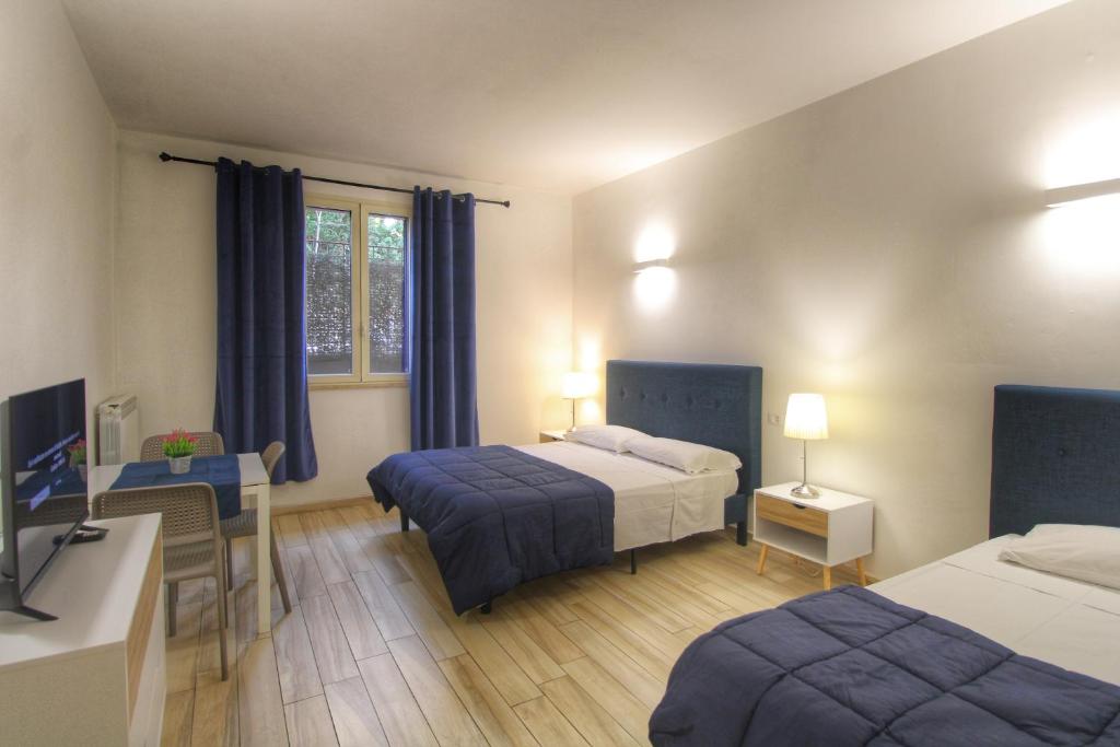 um quarto com 2 camas, uma secretária e uma televisão em Dalmati House San Lorenzo em Roma