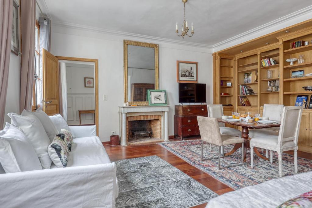 uma sala de estar com um sofá branco e uma mesa em Bohemian & Authentic Parisian Flat - Paris 07 em Paris
