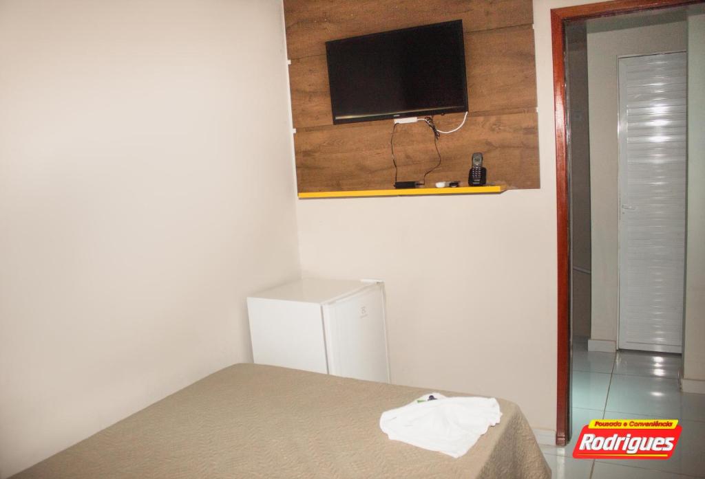 a room with a bed and a tv on a wall at POUSADA RODRIGUES in Barbalha