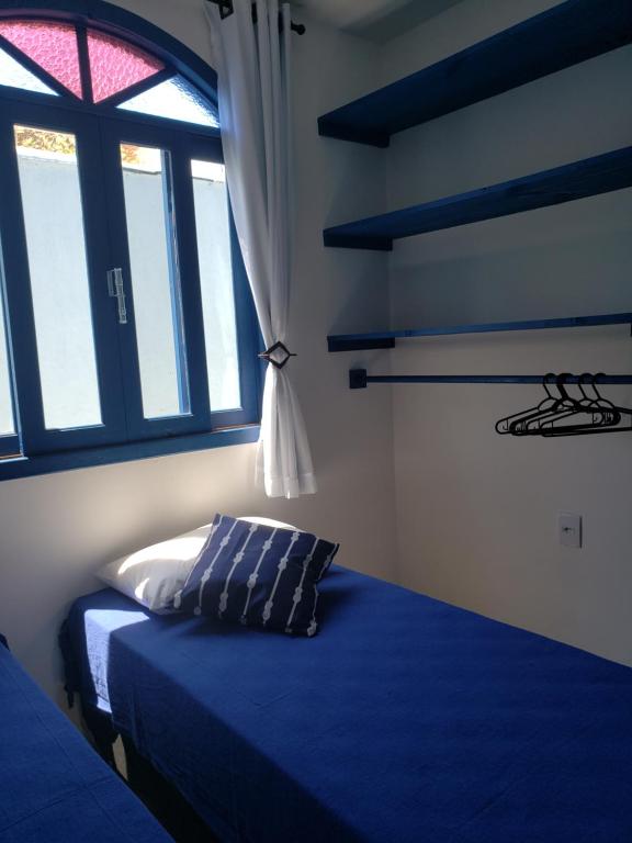 Un dormitorio con una cama azul y una ventana en Casa Miosótis apartamentos, en Palhoça