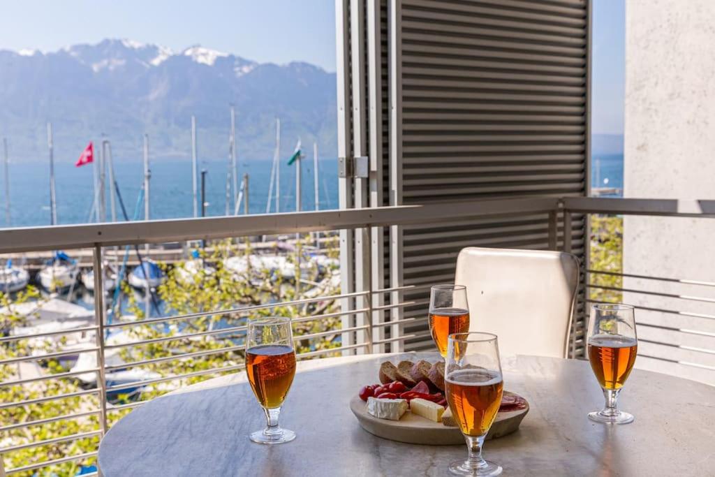 沃韋的住宿－Lakeside Apartment - Grand appartement familial avec terrasses et vue panoramique，两杯酒和一盘桌上的食物