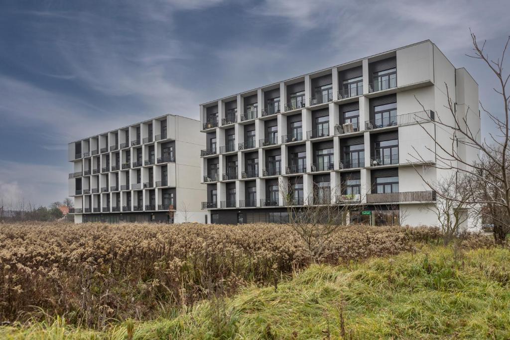 a white building with a field in front of it at Studia przy lotnisku od WroclawApartament-pl in Wrocław