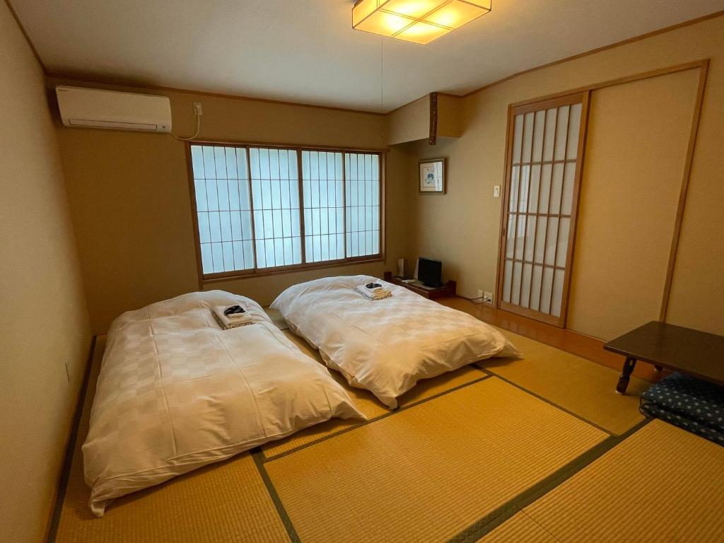 two beds in a room with two large windows at Hotel Fukudaya in Tokyo