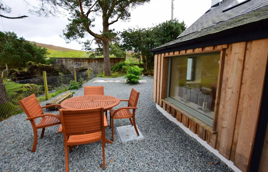 een patio met een tafel en stoelen naast een gebouw bij Bridge Cottage in Luib