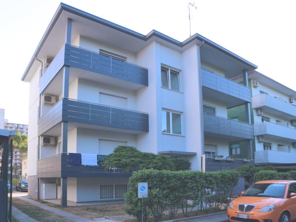 un condominio bianco con balconi blu e una macchina di Stiria a Lignano Sabbiadoro