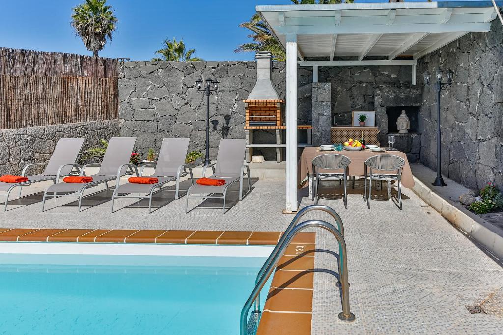 eine Terrasse mit einem Tisch und Stühlen neben einem Pool in der Unterkunft Sea Palms Lanzarote in Playa Blanca