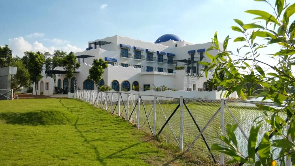 um edifício branco com uma cerca em frente a um quintal em Ananda Resorts em Srī Niketan