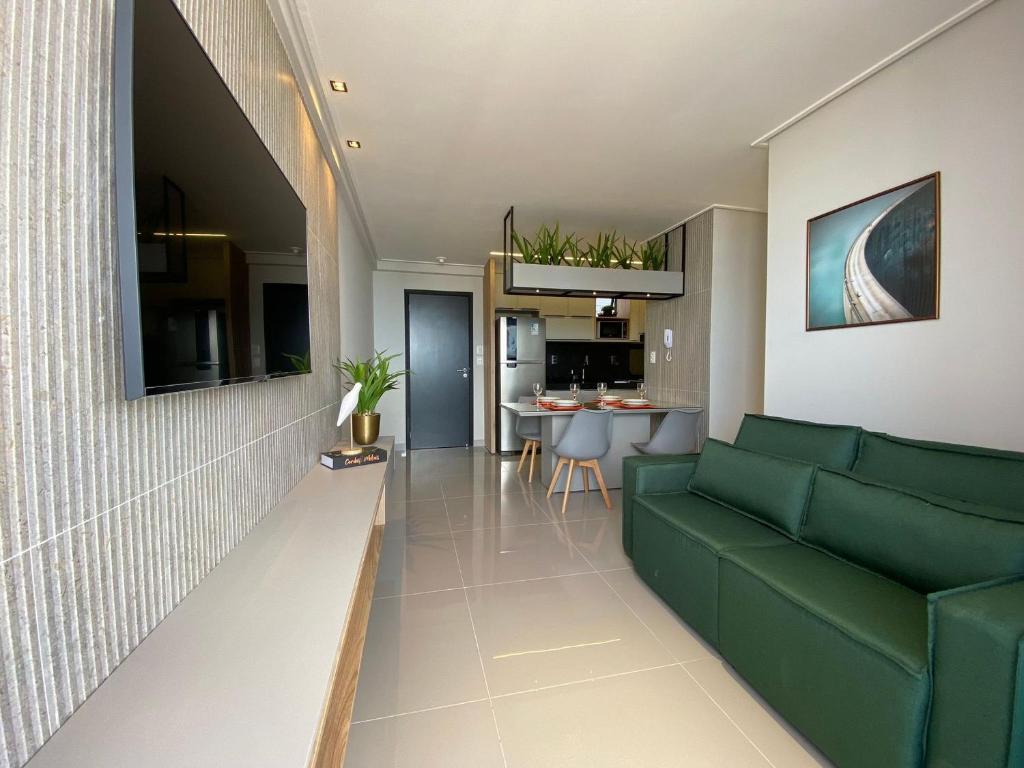 sala de estar con sofá verde y cocina en Bela Hospedagem - Lindo apt no One Way com vista incrível do mar, en João Pessoa