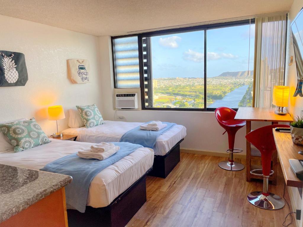 Habitación de hotel con 2 camas y ventana grande. en Cozy Hawaiian Monarch condo, en Honolulu