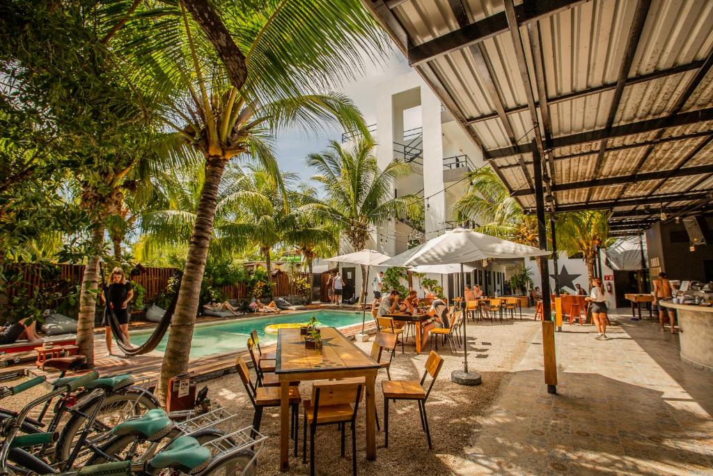 a resort with a pool and tables and chairs at Che Holbox Hostel & Bar Adults Only in Holbox Island