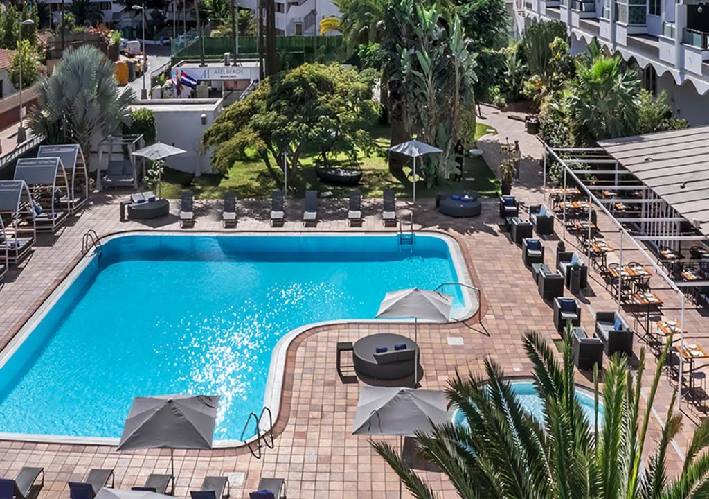 a pool with a pool table and chairs in it at AxelBeach Maspalomas - Apartments and Lounge Club - Adults Only in Playa del Ingles
