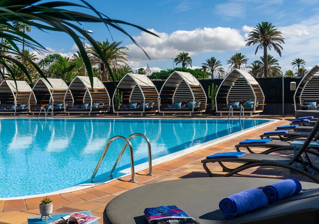 a swimming pool with chaise lounge chairs next to a resort at Axel Beach Maspalomas - Adults Only in Playa del Ingles