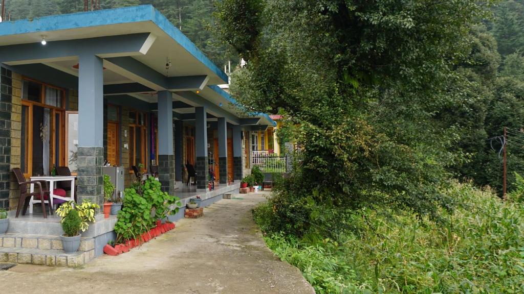 a house with a blue roof with plants in front of it at Angela's Boutique Homes Dharamkot in Dharamshala