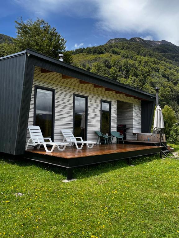 ein Haus mit einer Terrasse und Stühlen darauf in der Unterkunft Aysén Lodge - Cabaña con Tinaja in Puerto Dunn