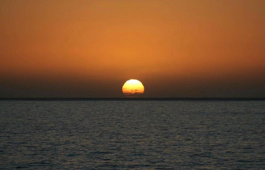MAKTUB SUNSET COTTAGE A في بول دو مار: غروب الشمس على المحيط مع الشمس في السماء
