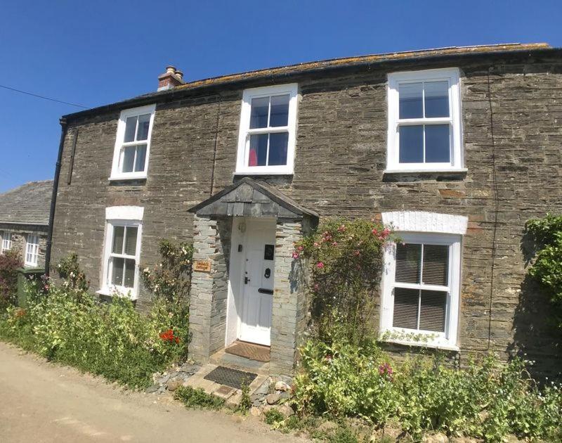 an old brick house with a white door and windows at Webbers in Padstow