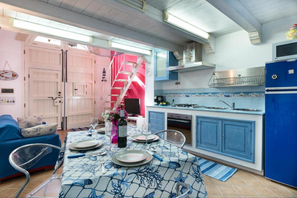 Una cocina con gabinetes azules y una mesa y sillas. en Cambusa del Capitano, en San Vito lo Capo