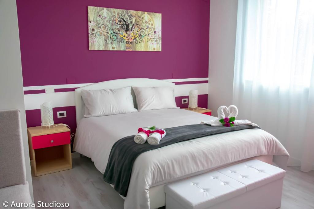 Un dormitorio con una cama blanca con paredes moradas en B&B L'incanto degli Artisti en Caltagirone