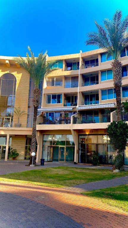 un gran edificio con palmeras delante en יולי גולף en Caesarea