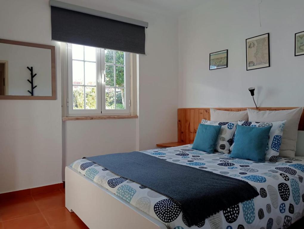 a bedroom with a large bed with blue pillows at casal do melro in Ericeira