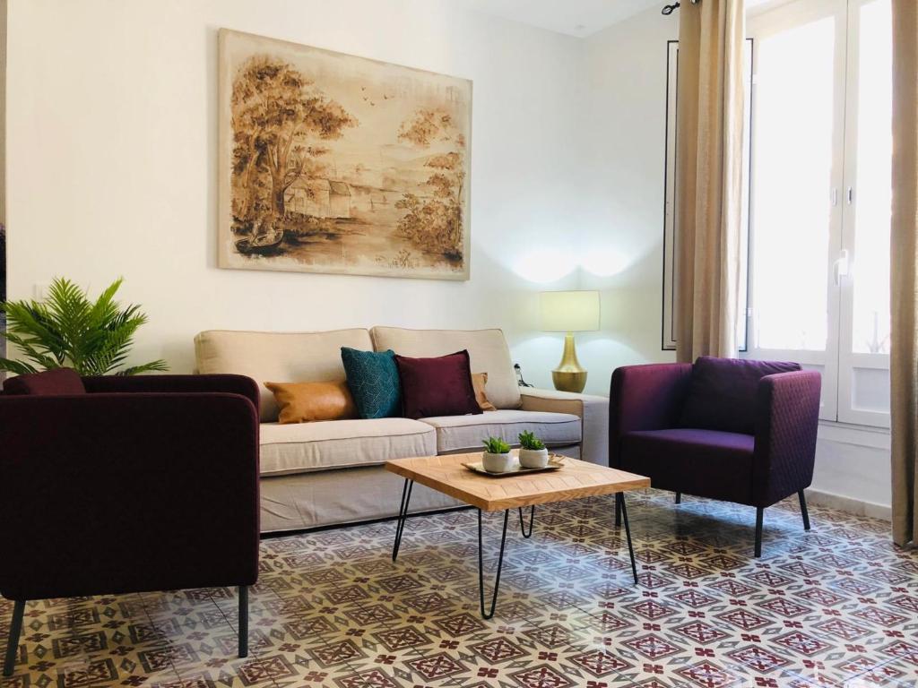 uma sala de estar com um sofá e duas cadeiras em Apartments Olé - Tetuán em Sevilha