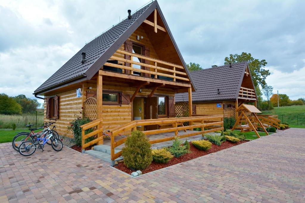 una cabaña de madera con una bicicleta estacionada frente a ella en Oaza Spokoju - Domki en Polanica-Zdrój