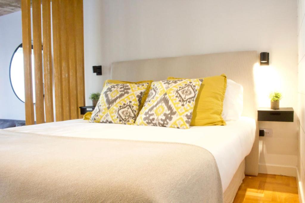 1 dormitorio con cama blanca y almohadas amarillas en Explore Palermo in Stunning and Chic Studio -1D- en Buenos Aires