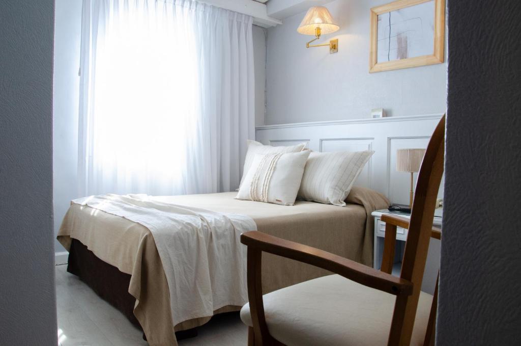 um quarto com uma cama, uma cadeira e uma janela em Hotel Valles em Mar del Plata