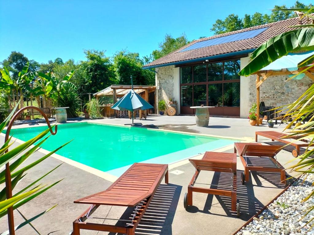 a swimming pool with wooden chairs and a house at Villa de 7 chambres avec piscine privee jardin amenage et wifi a Saint Jean de Marsacq in Saint-Jean-de-Marsacq