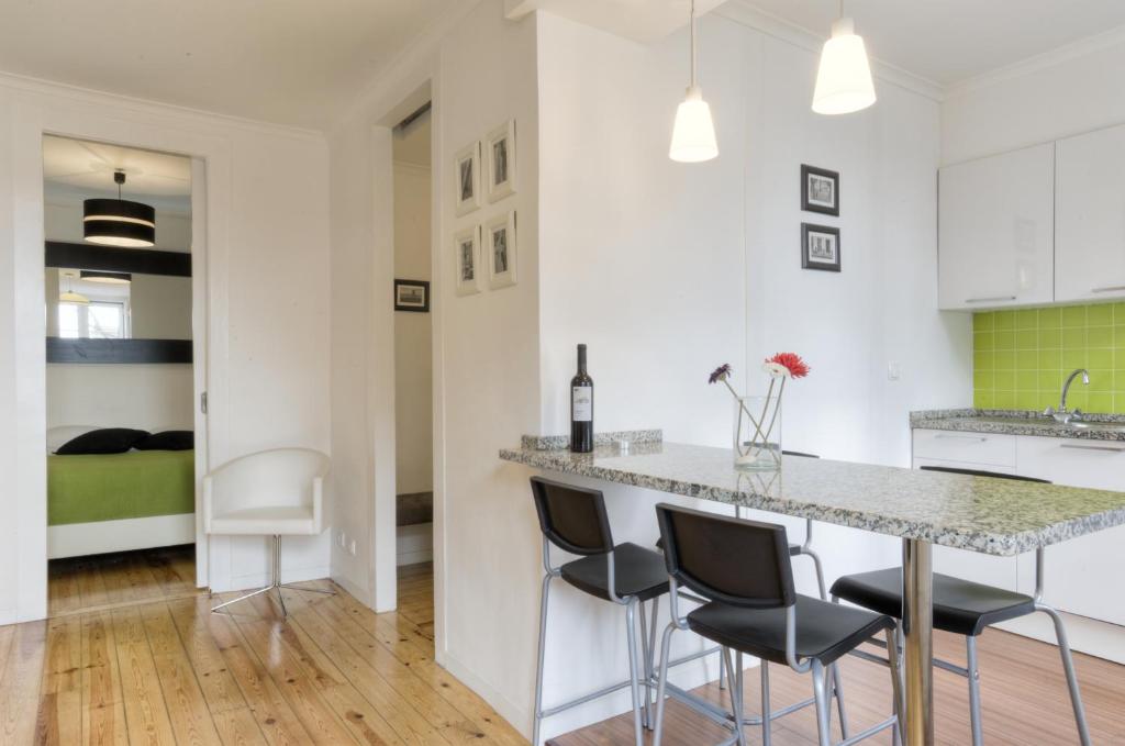 een keuken met witte kasten en een bar met barkrukken bij BmyGuest - Castelo Stylish Flat in Lissabon